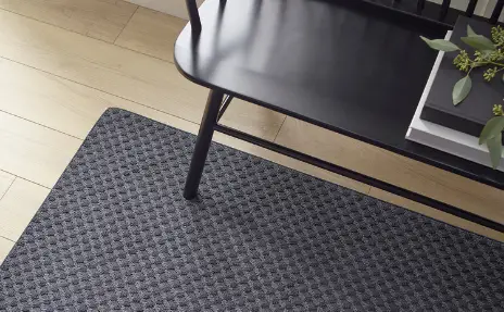 black textured runner area rug carpet under black bench in hallway with light wood flooring